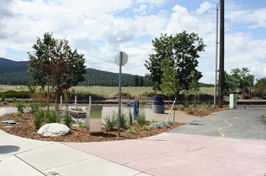 Paved North Idaho Centennial Trail path lined with young trees in Post Falls