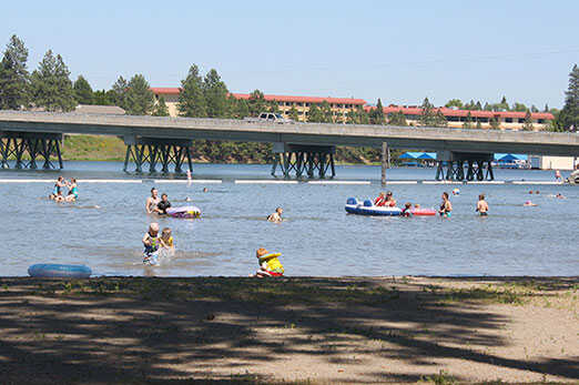 Swimmers and inner tubes at the Q’emiln Park beach on the Spokane River