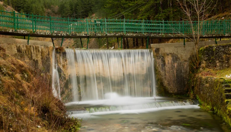 Falls Park Post Falls, Idaho: The Complete Visitor's Guide 1 Waterfall spilling over a small stone dam beneath a green footbridge in a wooded park